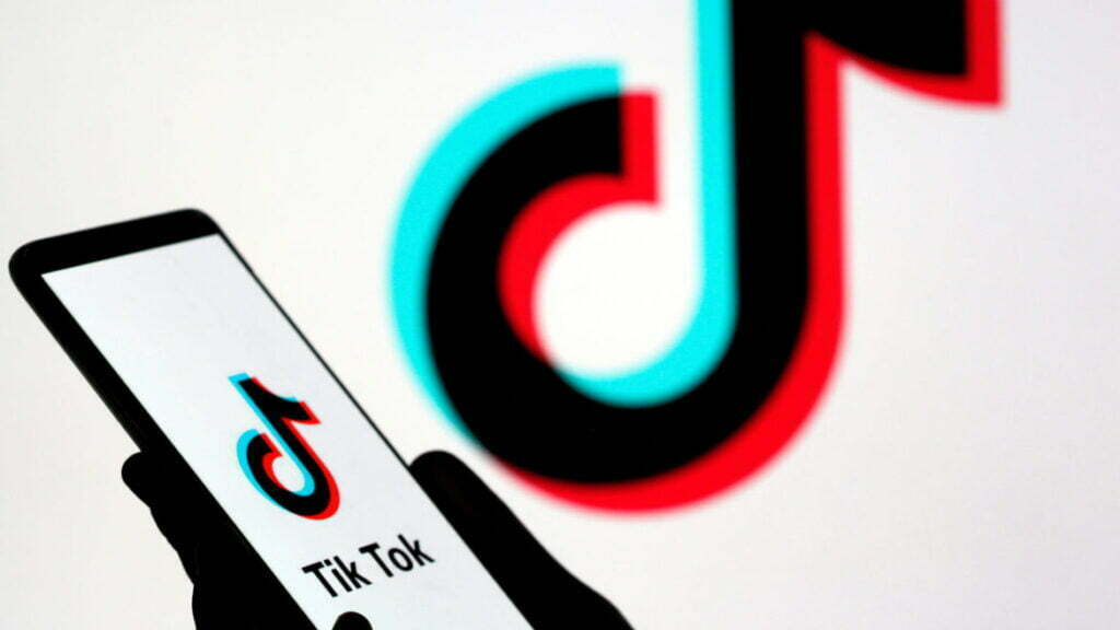 Person holds a smartphone with Tik Tok logo displayed in this picture illustration
