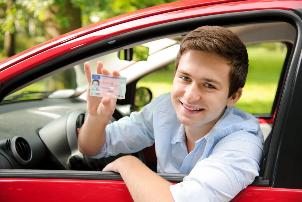 10355207 - teenager sitting in new car and shows his drivers license