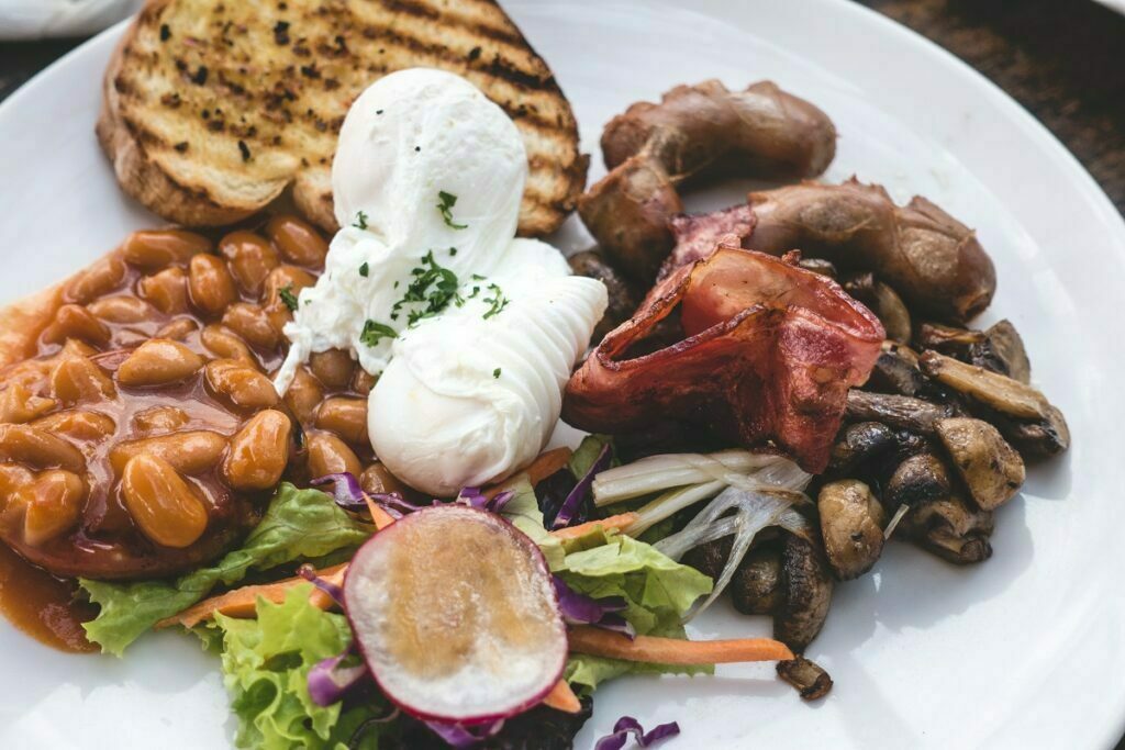 Filling brunch with poached eggs, beans, bacon, sausages and mushrooms