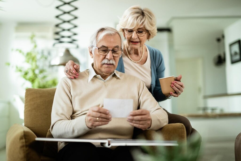 nostalgic-mature-couple-looking-their-photo-album-home
