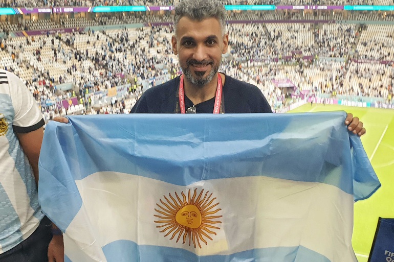 Fanul argentinian Hani Albashir ține steagul argentinian în tribune și zâmbește
