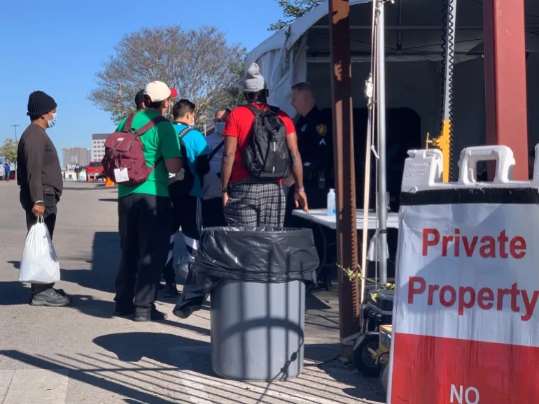Migranții stau în fața Centrului de Resurse pentru Migranți San Antonio din San Antonio, Texas