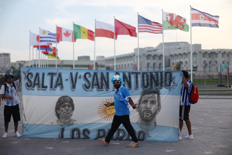 Fotbal Fotbal - Previzualizarea Cupei Mondiale FIFA Qatar 2022, Doha, Qatar - 17 noiembrie 2022 Un fan argentinian pozează în fața unui steag al argentinianului Lionel Messi și al fostului jucător Diego Maradona REUTERS/Hannah Mckay
