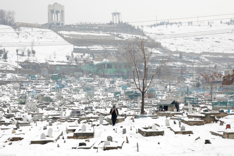 Un afgan trece printr-un cimitir înzăpezit din Kabul